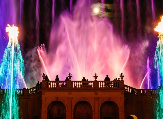 A fountain show at Longwood featuring uplight fountains in pink, blue, and teal lights. 