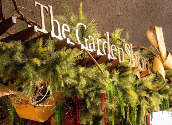 The sign reads The Garden Shop in gold lettering, with holiday foliage draaped around it.