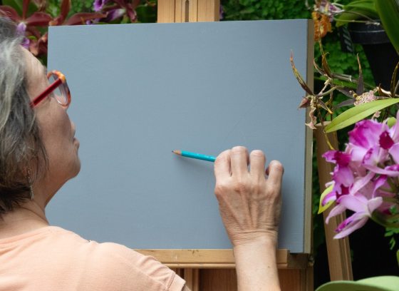 A person in front of an easel, getting ready to sketch orchids.