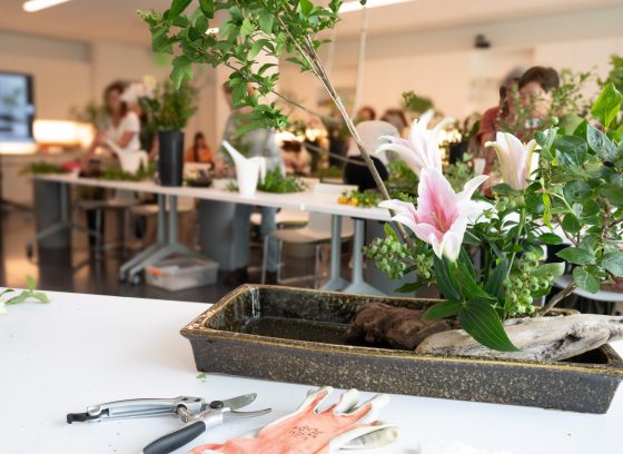 An ikebana creation, in a shallow gray tray, in a classroom.
