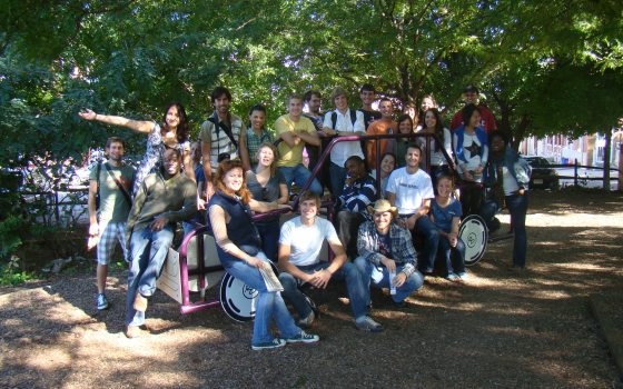 large group of students posing in front of a bunch of green trees