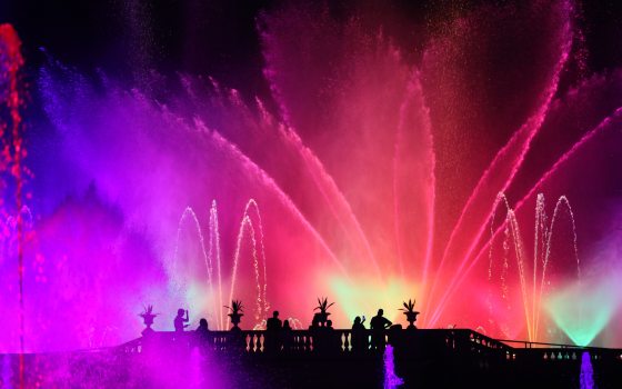 a nighttime fountain show with red, purple, and green lights 