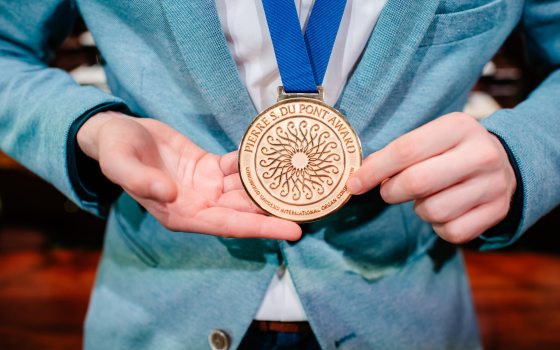 close up of a person in a blue suit jacket wearing a gold medal on a blue ribbon