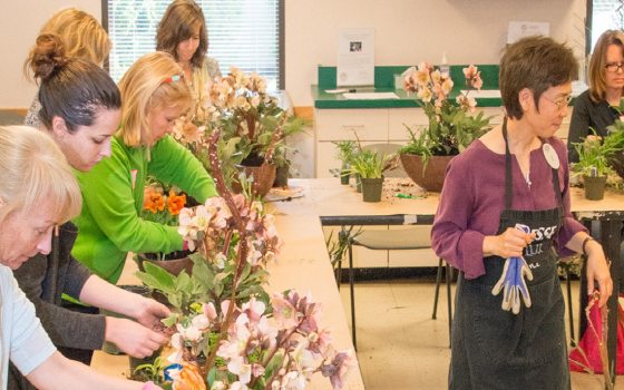 person leading a floral design class with several students facing them