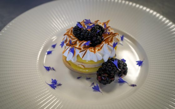 pastry sitting on a plate with whipped cream and blackberries on top