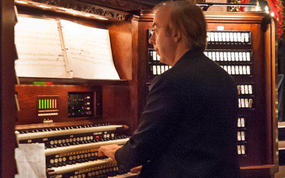  a person seated at an organ console, hands on the keys