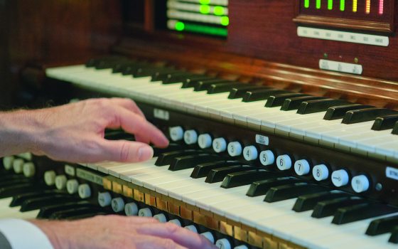 closeup of organ console, with hands on the keys