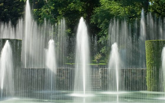 fountains rising from a stage surrounded by garden greenery