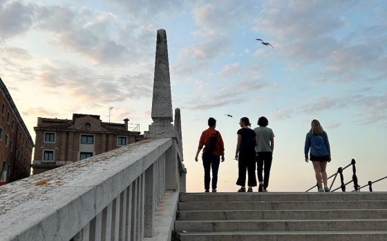 Four people at the top of an outdoor stone staircase walking away from the camera.