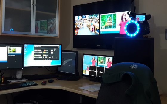 A desk setting with several monitor, a tv, and camera equipment.