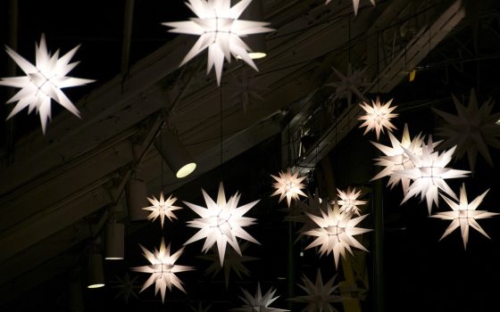 A night sky with white lit star ornaments.