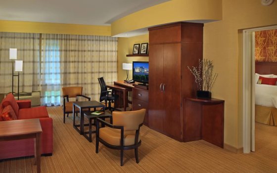 The interior of a hotel room with a desk, chair, and bed.