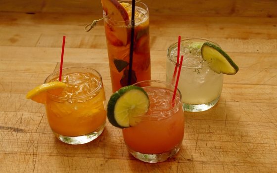 Four cocktails in glasses on a wooden table.