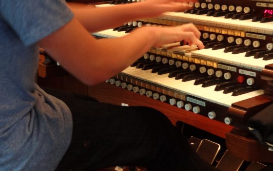 A person seated at an organ playing the keys.