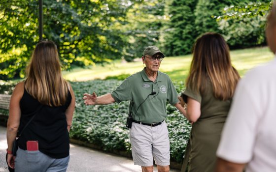 A person in a green shirt leading a tour outdoors.