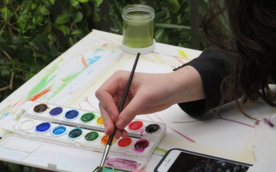 Person mixes watercolors in a tray