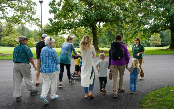 A group of people, kids and adults, walking on a paved path through Longwood Gardens.