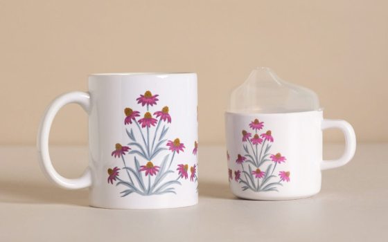 Two mugs with pink painted flowers on them.