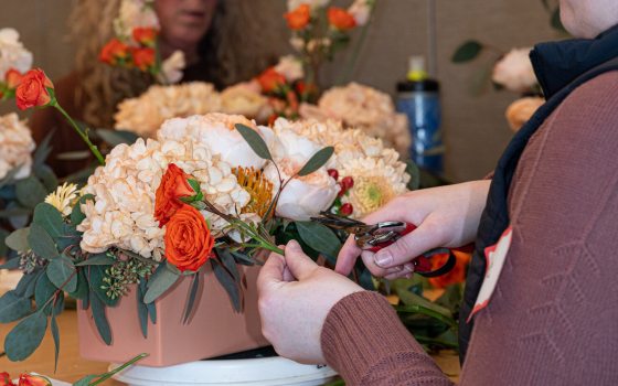 A person using floral snips to create a floral centerpiece.