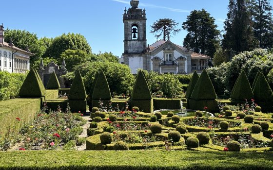 A topiary garden with an old stone building behind it located in Portugal.