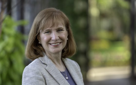 Lady with reddish blonde hair wearing a light colored suit smiling at the camera