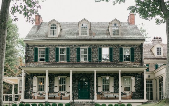 A two-story stone farmhouse in a picturesque setting.