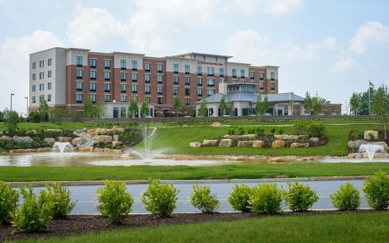 A hotel set in the distance with a pond and fountains in the foreground.