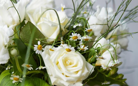 An floral centerpiece featuring white roses and green foliage.