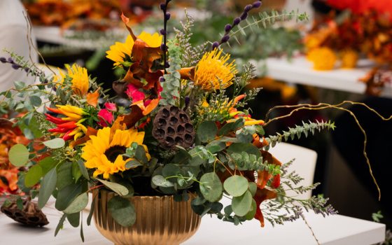 A floral arrangement featuring sunflowers in a gold vase.
