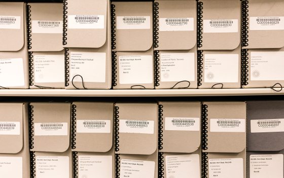 Tan numbered archive boxes aligned on a shelf.