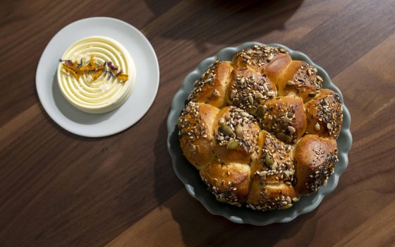 Shot from above of pull apart bread covered with seeds in a circular dish.