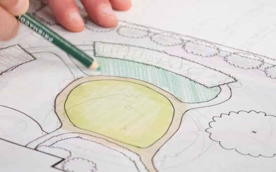 A person drawing a sketch of a landscape design.