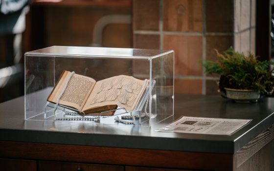 A book propped open, placed under a glass case. 