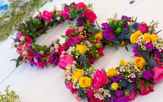 Two floral wreaths with vibrant flowers displayed on a table.