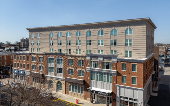 A small hotel in two shade of brown and tan set on a city block. 
