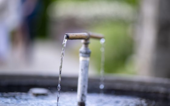 A t-shaped water fountain, with water coming our of both ends of the "t" into a pot. 