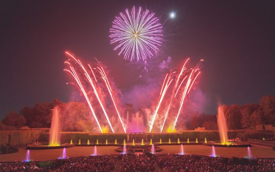 Fountains and fireworks in hues of yellow, red, and violet, with angled fireworks mimicking fountains and framing a large round central fireburst.