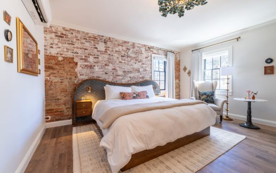 The interior of a hotel room, featuring a welcoming room, king bed, and brightly lit. 