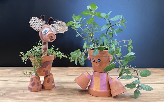 Giraffe and person crafted out of small terracotta pots planted with herbs