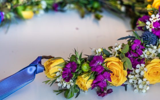 A floral crown being crafted out of purple, yellow, and white flowers. 