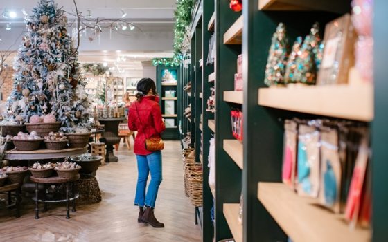 A person in a red jacket browsing shelves of holiday merchandise.