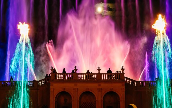 A fountain show at Longwood featuring uplight fountains in pink, blue, and teal lights. 