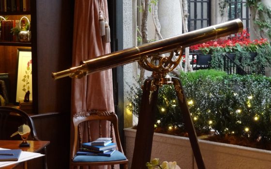 A telescope aimed outside a window in an office study. 