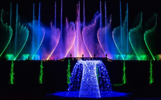 a wall of fountains that glow colors of green, blue, purple, and pink 
