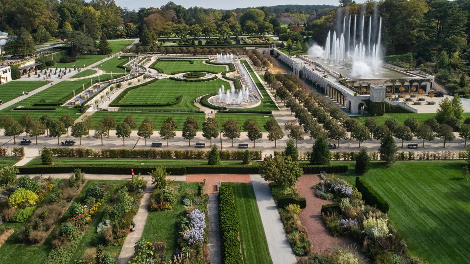 Aerial view of a large fountain garden to the upper right, a topiary garden at the top, and a lined flower bed garden at the bottom