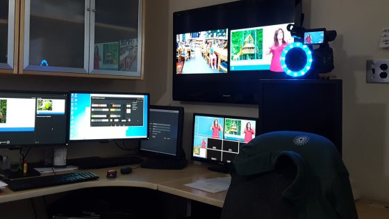 A desk setting with several monitor, a tv, and camera equipment.