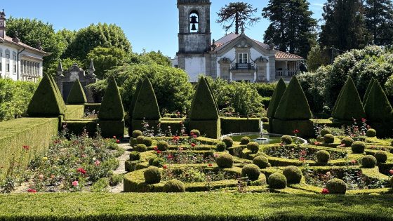 A topiary garden with an old stone building behind it located in Portugal.