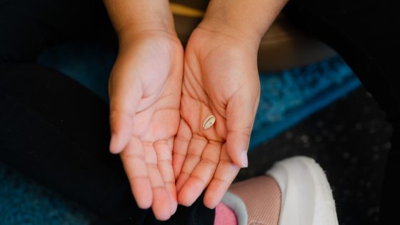 A pair of cupped hands holding a single, small, light-colored seed, shown from a top-down perspective during a children's activity.