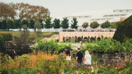 Three people walking through a lush late summer garden at Longwood Gardens. 