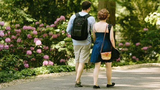 two people walking on a path through a garden